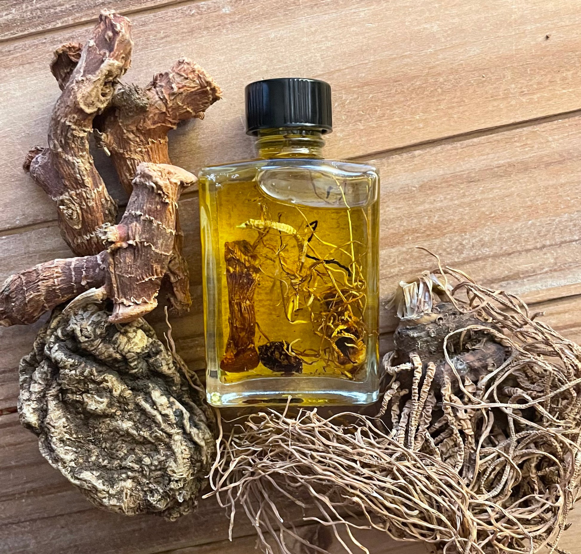 Triple John Oil bottle displayed with High John the Conqueror root, Galangal root, and Beth Root showing the three powerful hoodoo ingredients used in this conjure oil