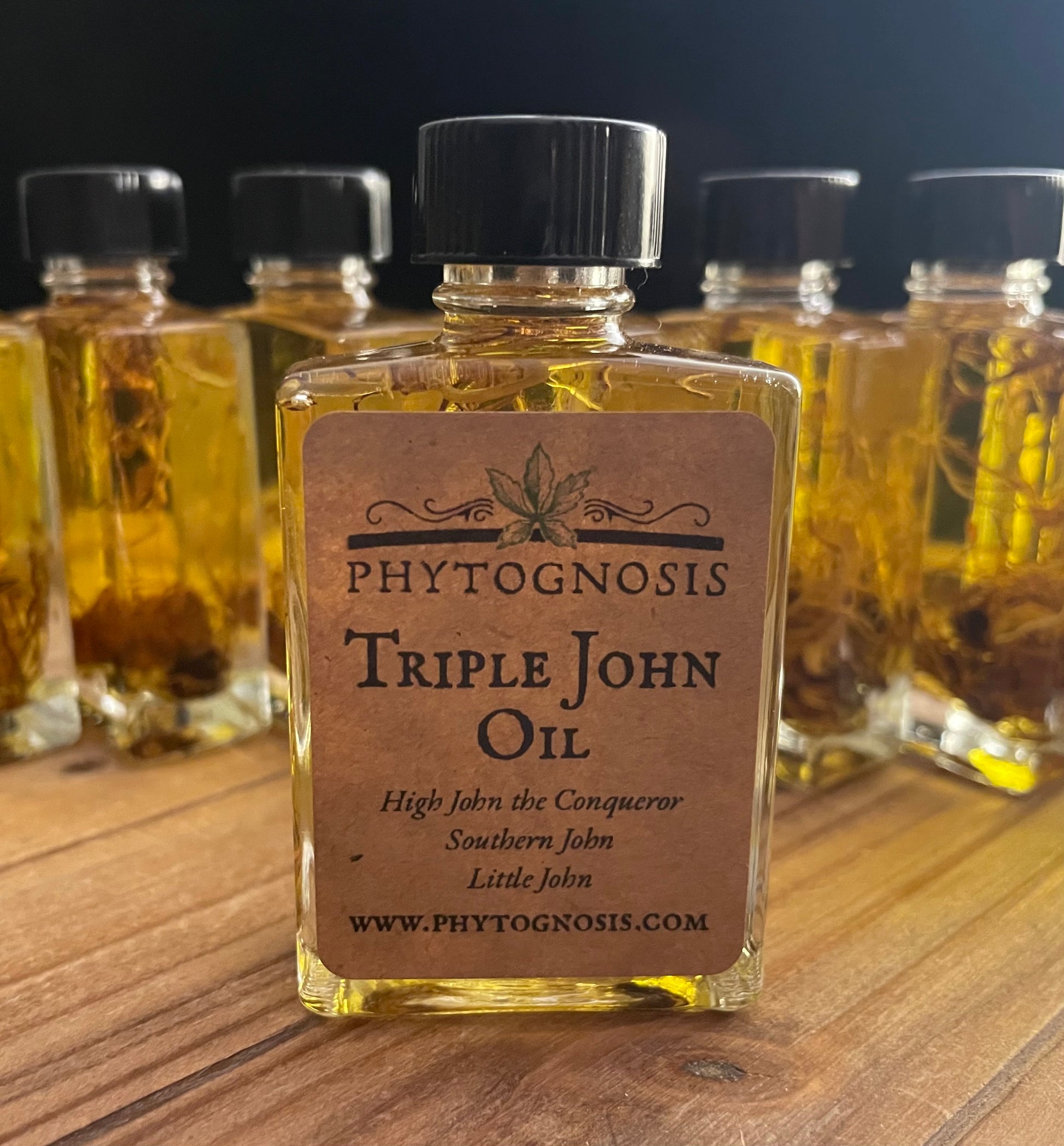 Bottle of Phytognosis Triple John Oil on a wooden surface with multiple bottles in the background.